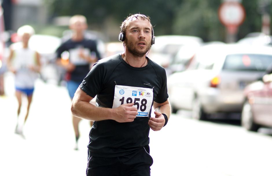 A male runner wearing headphones participates in a street marathon, full of determination.